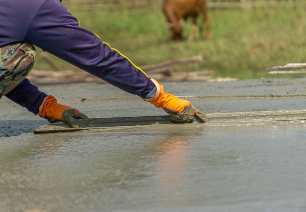 A man pouring concrete onto a road, showcasing the work of Concrete Driveway Contractors.