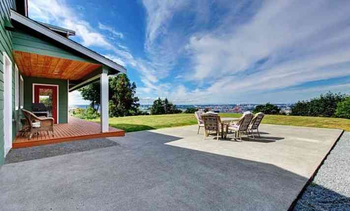 Contemporary home featuring a parked car and a concrete patio, highlighting modern architecture.