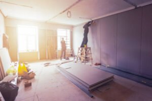 A man works on a wall in a room, showcasing the services of a construction and remodeling company.