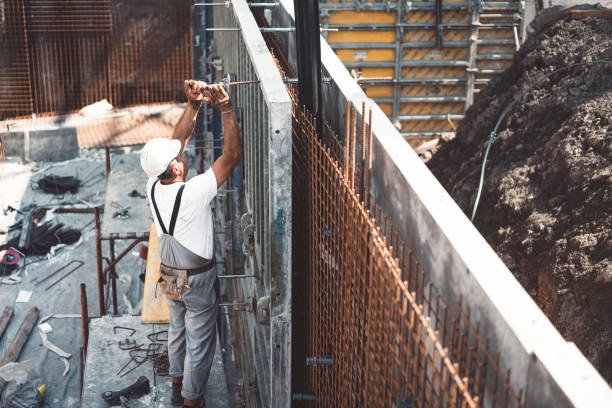 Construction worker on scaffolding, focused on load-bearing wall construction at a busy construction site.