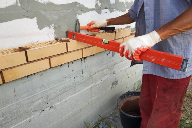 A man constructs a load-bearing wall by placing bricks carefully to create a sturdy structure.