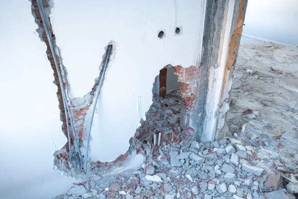 A hole in a load-bearing wall of a house, revealing the interior structure and potential structural concerns.