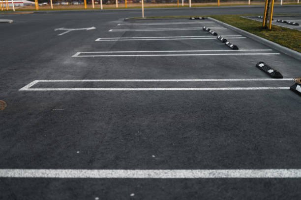 A vacant parking lot marked with white lines, accompanied by a sign indicating driveway repair services.