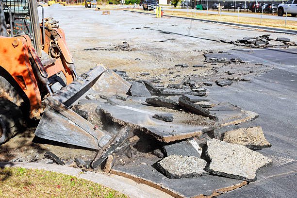 A bulldozer is engaged in road work, focusing on repairing a concrete walkway.