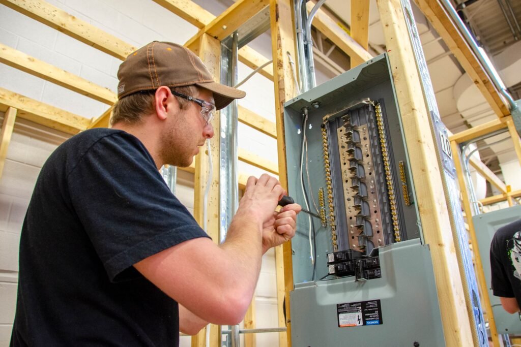 A general contractor is working on an electrical power panel inside a building.
