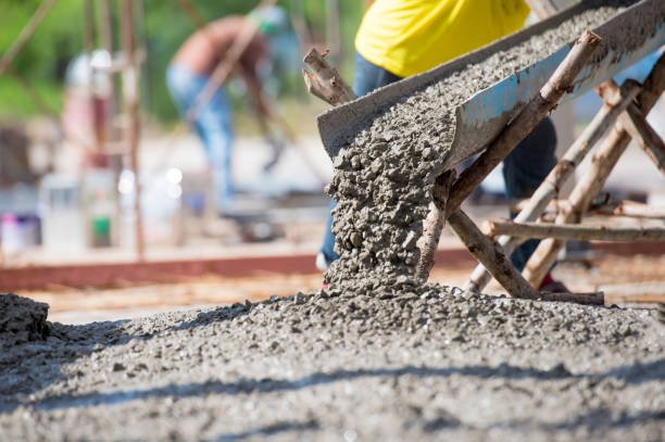 A man pouring concrete into a mixer, showcasing full-service concrete construction in progress.